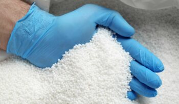 A hand with a blue glove inside nitrate Ammonium bag